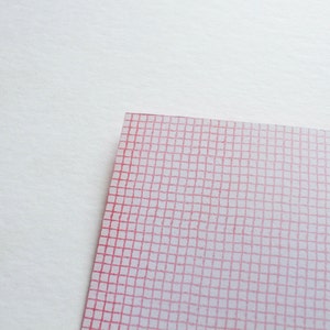 May include: A corner of a white and pink grid pattern on a white background. The grid is composed of thin, red lines forming small squares. The paper has a slightly translucent quality.