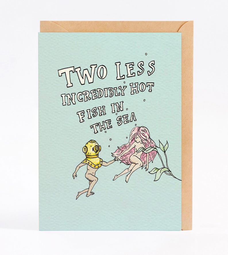 May include: A light blue greeting card with a cartoon illustration of a mermaid and a diver. The card reads "Two Less Incredibly Hot Fish In The Sea."