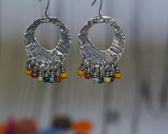 Pendientes artesanales de metal plateado antiguo con cuentas de vidrio multicolor.