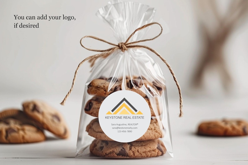 Pu&ograve; includere: Un sacchetto trasparente di cellophane legato con spago, pieno di biscotti con gocce di cioccolato. Un adesivo rotondo con il testo "KEYSTONE REAL ESTATE" &egrave; sul sacchetto. Il testo "You can add your logo, if desired" &egrave; in alto.
