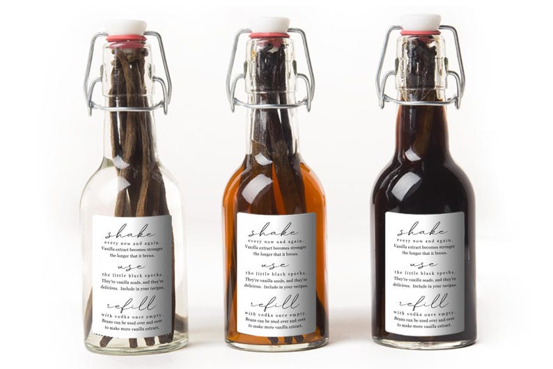 May include: Three clear glass swing-top bottles containing dark vanilla beans. Each bottle features a white rectangular label with black text that reads: shake every now and again, use the little black specks, and refill with vodka once empty.