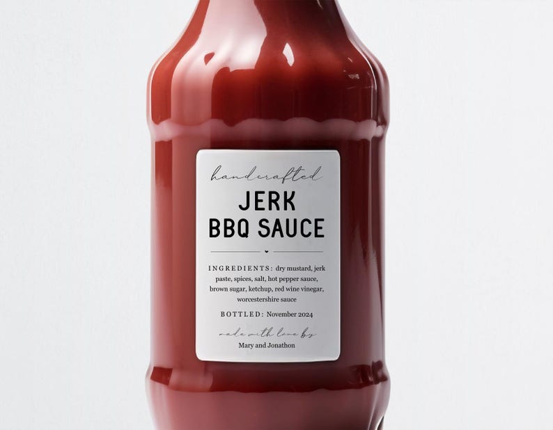 K&ouml;nnte beinhalten: Eine Glasflasche mit roter Jerk-BBQ-Sauce und einem wei&szlig;en Etikett mit der Aufschrift "handcrafted JERK BBQ SAUCE". Das Etikett enth&auml;lt auch die Zutaten und das Abf&uuml;lldatum: November 2024. Auf dem Etikett steht "made with love by Mary and Jonathon".