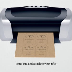 Puede incluir: Una impresora plateada y negra imprimiendo cuatro etiquetas de regalo marrones. Cada etiqueta tiene un gr&aacute;fico de casa y las palabras "Happy Holidays" y "simply..." impresas. El texto en la parte inferior de la imagen dice "Imprime, corta y adjunta a tus regalos."