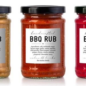 May include: Three glass jars with labels reading "handcrafted BBQ RUB". The jars are filled with different coloured sauces: a yellow sauce, a red sauce, and a red sauce. The labels also list the ingredients and preparation date.
