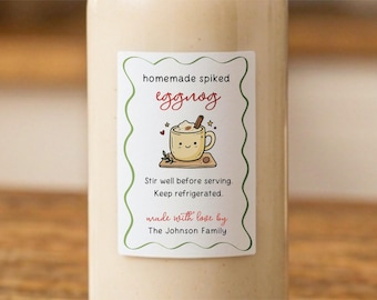 May include: A clear bottle containing a beige liquid with a rectangular label. The label has a green wavy border and text reading homemade spiked eggnog, Stir well before serving. Keep refrigerated. made with love by The Johnson Family.