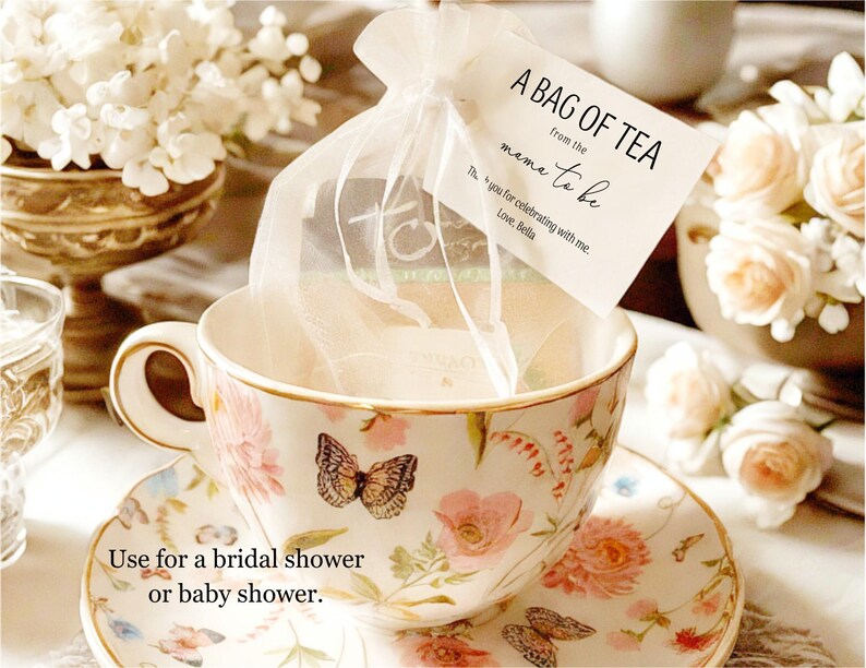 Puede incluir: Una bolsita de t&eacute; blanca en una bolsa blanca transparente con una taza de t&eacute; y un platillo blancos con dise&ntilde;os florales. La bolsita de t&eacute; tiene una etiqueta que dice "A Bag of Tea from the Mom-to-be. Thanks for celebrating with me. Love, Bella."  Util&iacute;zala para una despedida de soltera o un baby shower.
