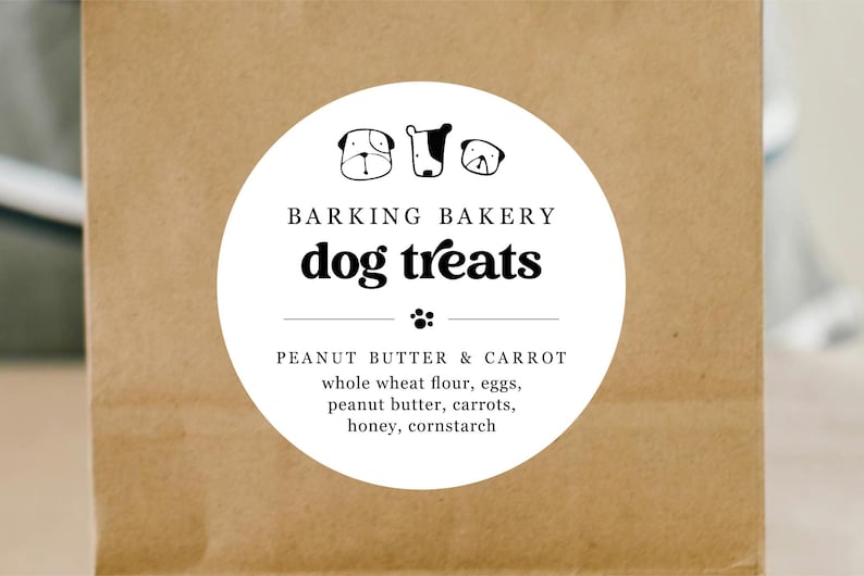May include: A white round sticker with black text and illustrations of dogs. The sticker says "Barking Bakery dog treats" and lists the ingredients: "Peanut Butter & Carrot, whole wheat flour, eggs, peanut butter, carrots, honey, cornstarch."