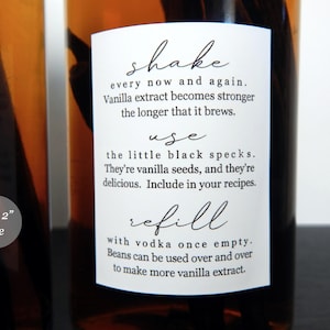 May include: A white rectangular label on an amber glass bottle containing vanilla beans. The label features black text: shake every now and again, use the little black specks, and refill with vodka once empty. A small circular icon states 3.8 x 5.1 cm size.