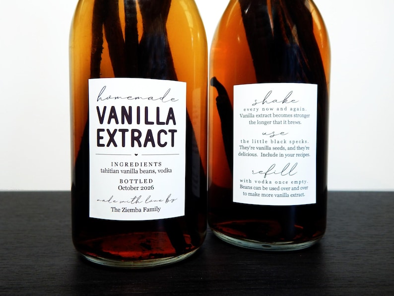 May include: Two clear glass bottles filled with amber liquid and dark vanilla beans. The front label reads Homemade Vanilla Extract, ingredients Tahitian vanilla beans, vodka, bottled October 2026, made with love by The Ziemba Family. The side label provides instructions to shake, use, and refill.
