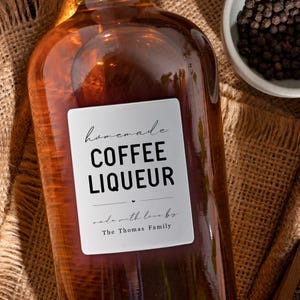 May include: A brown glass bottle with a white label that reads "homemade coffee liqueur made with love by The Thomas Family".
