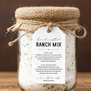 May include: A clear glass jar filled with white ranch mix, topped with a burlap lid and twine. A white tag reads "handcrafted RANCH MIX" with instructions for dip and dressing. The jar is on a wooden surface.