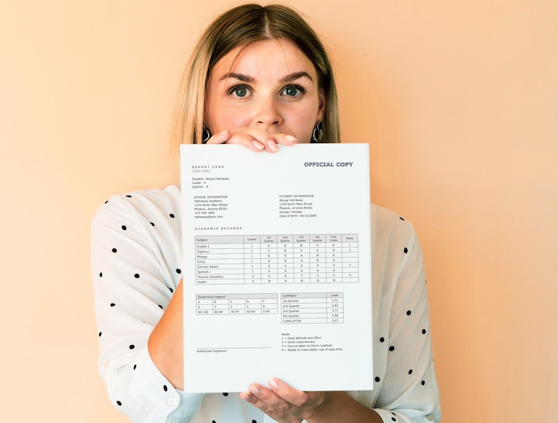 May include: A woman holds up a report card with the words "OFFICIAL COPY" at the top. The report card shows the student's name, grade, school information, and academic record.