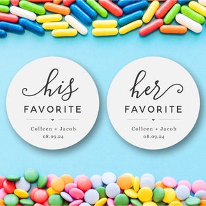 May include: Two white round stickers with black text. The left sticker says "his favorite" with the names "Colleen + Jacob" and the date "08.09.24" below. The right sticker says "her favorite" with the same names and date below. The stickers are on a light blue background with colorful candy sprinkles above and below.