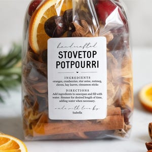 May include: A clear cellophane bag filled with stovetop potpourri ingredients, including orange slices, cinnamon sticks, and star anise. The label reads "Handcrafted Stovetop Potpourri" with instructions and ingredients.