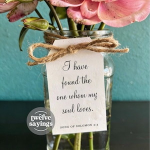 May include: A glass jar with pink flowers and green stems. A white tag tied with twine reads "I have found the one whom my soul loves." The text is from Song of Solomon 3:4. The jar has a "twelve sayings" logo.
