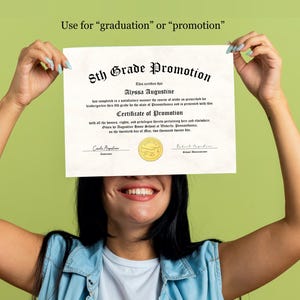 May include: A white certificate with a gold seal, reading "5th Grade Promotion" and "Certificate of Promotion". The certificate is being held up by a person, covering their face.
