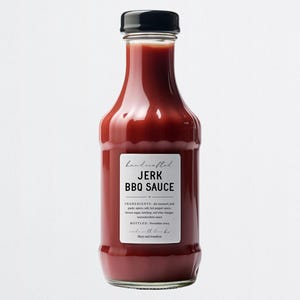 K&ouml;nnte beinhalten: Eine Glasflasche mit handgemachter Jerk-BBQ-Sauce und schwarzem Deckel. Das Etikett ist wei&szlig; mit schwarzem Text, der "handcrafted JERK BBQ SAUCE" lautet. Die Zutaten sind auf dem Etikett aufgelistet.