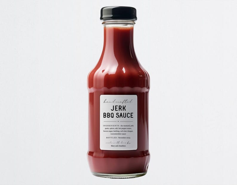 K&ouml;nnte beinhalten: Eine Glasflasche mit handgemachter Jerk-BBQ-Sauce und schwarzem Deckel. Das Etikett ist wei&szlig; mit schwarzem Text, der "handcrafted JERK BBQ SAUCE" lautet. Die Zutaten sind auf dem Etikett aufgelistet.