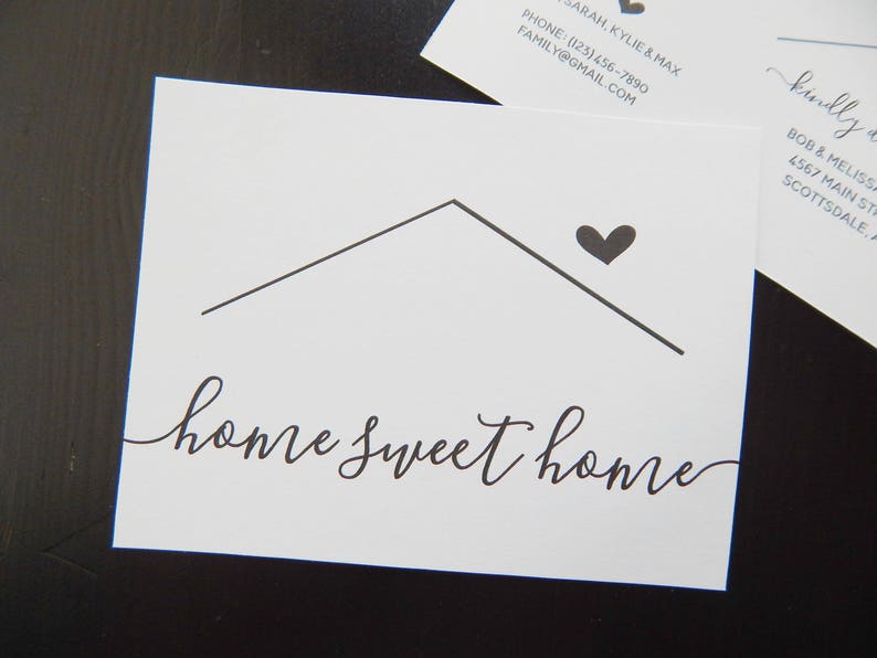 May include: A white card with a black house outline and a black heart above it. The text "home sweet home" is written in black cursive script.