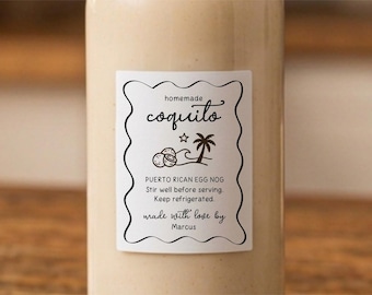 May include: A clear glass bottle filled with a beige liquid, featuring a white rectangular label with a scalloped black border. The label reads: homemade coquito, PUERTO RICAN EGG NOG, Stir well before serving. Keep refrigerated. made with love by Marcus.