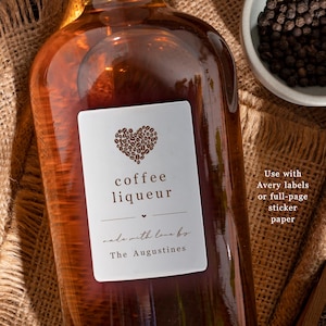 May include: A brown glass bottle with a white label that says "coffee liqueur" and "made with love by The Augustines". The label features a heart shape made of coffee beans.