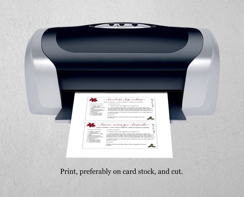 May include: A black and silver printer printing two recipe cards. The cards feature text and decorative elements in red. The bottom of the image has the text: "Print, preferably on card stock, and cut."