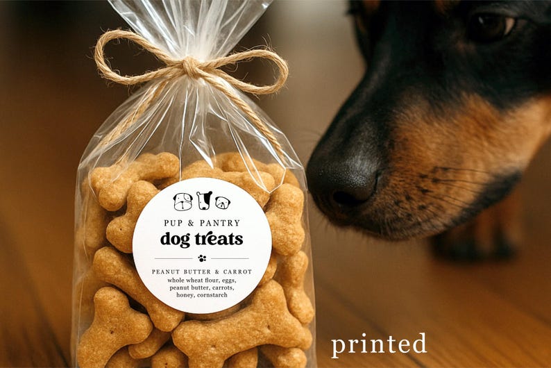 May include: A clear cellophane bag tied with twine, filled with bone-shaped dog treats. The label reads "Pup & Pantry dog treats" with peanut butter and carrot ingredients. A dog's nose is visible in the background.