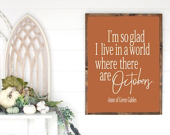 May include: A rustic wooden sign with a burnt orange background and white text. The sign reads "I'm so glad I live in a world where there are Octobers." - Anne of Green Gables.