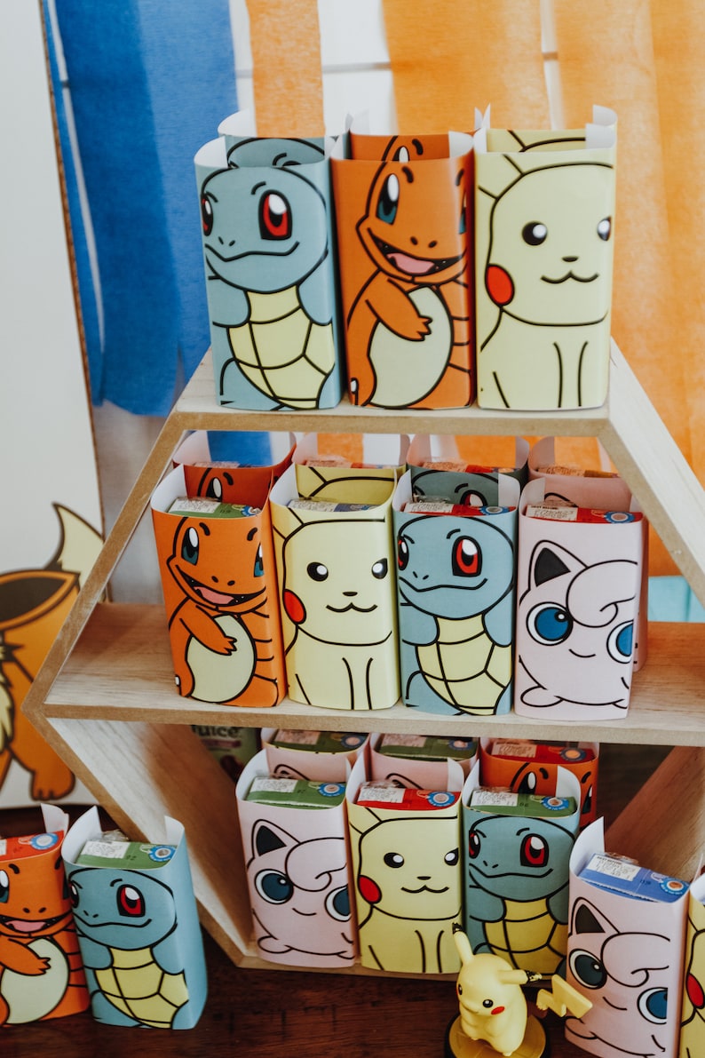 May include: A set of colourful juice boxes featuring various Pokemon characters. The boxes are displayed on a hexagonal wooden shelf.