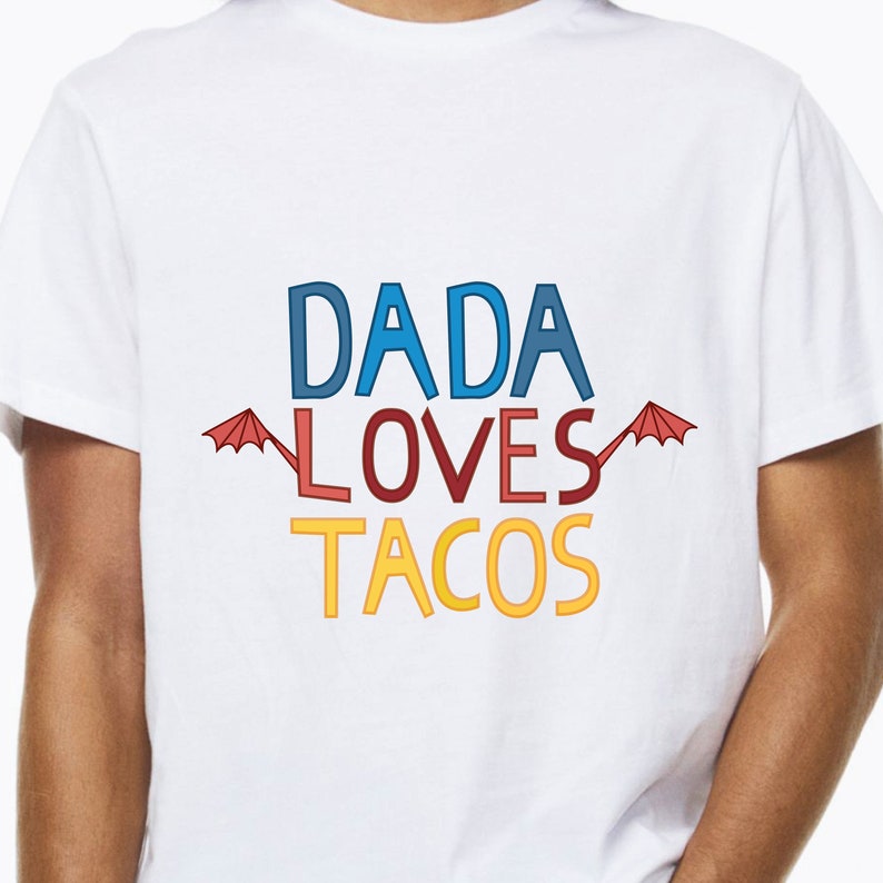 Puede incluir: Camiseta blanca con el texto "DADA LOVES TACOS" en letras de colores. El texto est&aacute; rodeado de dos paraguas rojos.