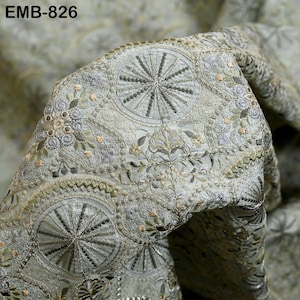 May include: Close-up of intricately embroidered fabric in shades of pale green, silver, and gold. The design features repeating circular patterns with radial lines and floral motifs. The text "EMB-826" is visible in the upper left corner.