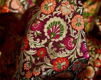 Può includere: Tessuto di broccato color borgogna con un motivo floreale in tonalità di arancio, rosa, verde e oro. Il tessuto ha una lucentezza discreta e una sensazione di lusso.