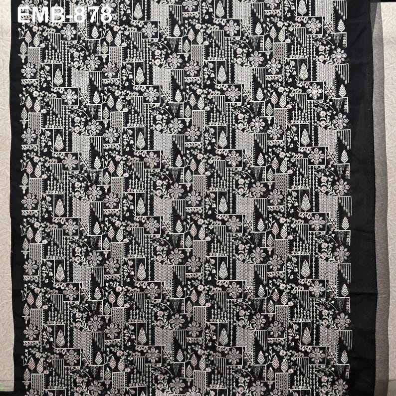May include: Black fabric with a detailed white floral and geometric pattern. The design features repeating floral and geometric shapes, creating a textured appearance. The text "EMB-878" is visible in the upper left corner.