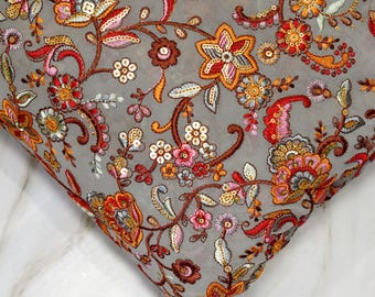 Puede incluir: Una tela gris transparente con un patrón de bordado floral en tonos rojos, naranjas, rosas y marrones. El bordado presenta detalles intrincados y lentejuelas.