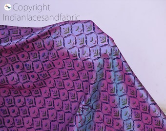 May include: Purple and blue iridescent fabric with a repeating floral pattern. The fabric has a subtle sheen and a soft texture.