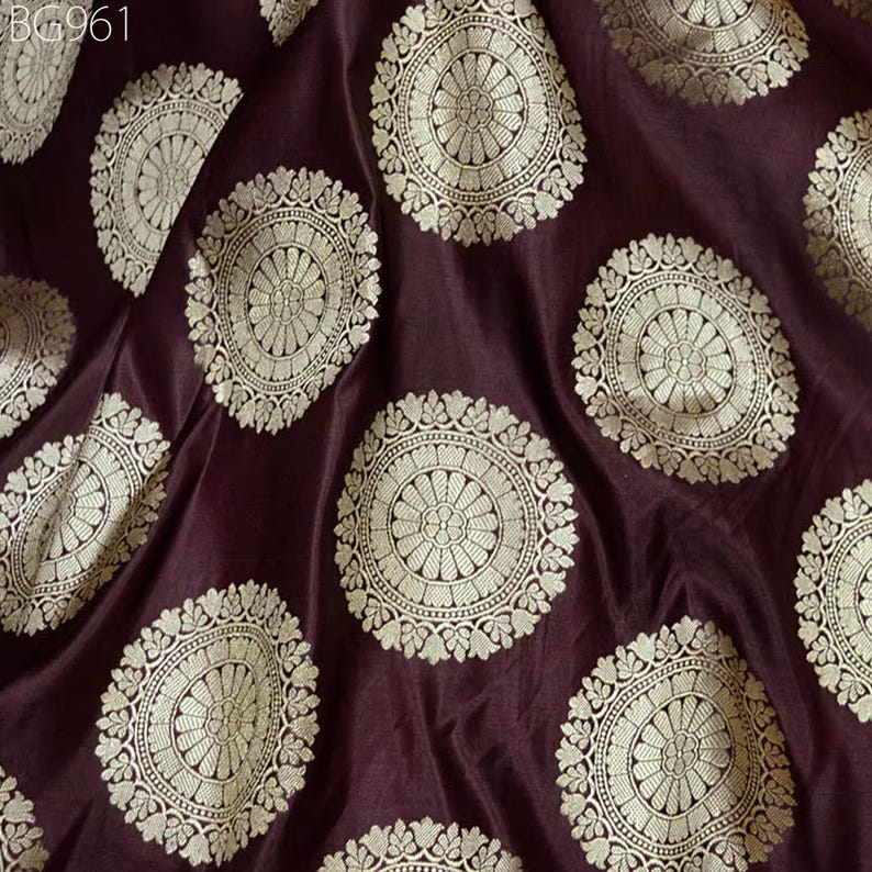 May include: Burgundy silk fabric with a repeating pattern of gold circular brocade designs.
