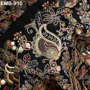 May include: Black fabric with detailed floral embroidery and sequin detailing. The design includes paisley and botanical patterns in gold, pink, blue, and green. The text "EMB-910" is visible in the upper left corner.