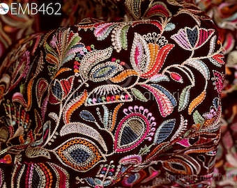 Op de afbeelding: Close-up van een bordeauxrode stof met ingewikkelde, kleurrijke borduursels. Het ontwerp toont bloemen- en paisley-patronen in tinten oranje, roze, groen en blauw. De tekst "EMB462" is zichtbaar linksboven.