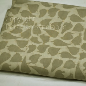 May include: A beige fabric with a leaf pattern printed in a darker beige color. The fabric is folded in half and the pattern is visible on both sides.