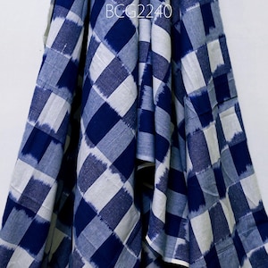 May include: Blue and white checked fabric with a subtle ikat pattern. The fabric is folded and draped, showing the texture and design.