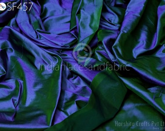 May include: A close-up of a fabric with a color-shifting effect, transitioning between shades of blue and green. The fabric is heavily draped, creating deep shadows and highlights. The text "SF457" is visible in the upper left corner.