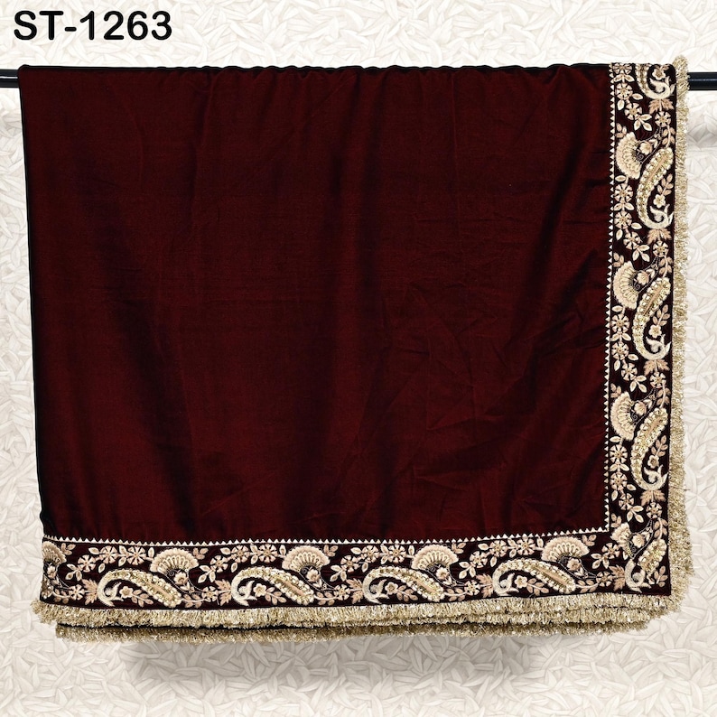 May include: A burgundy velvet shawl with intricate gold embroidery along the edges. The embroidery features paisley and floral designs, and the shawl has a gold fringe. The text "ST-1263" is visible in the upper left corner.