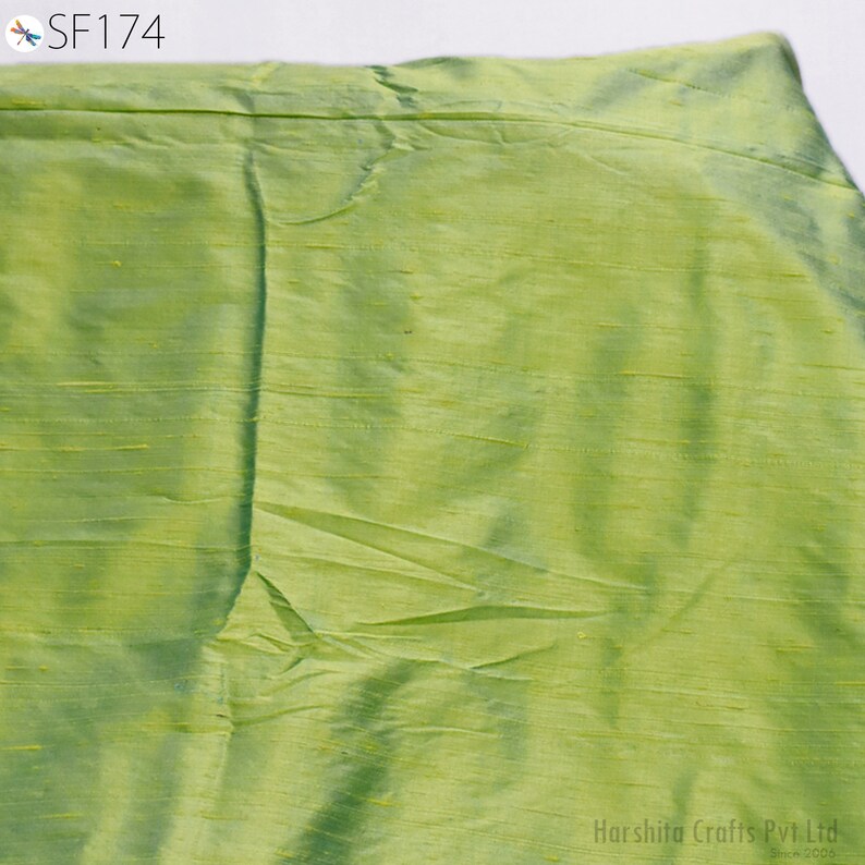 May include: A close-up of a light green fabric with a subtle sheen. The fabric has a smooth, silky texture.