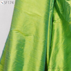 May include: A close-up of a green silk fabric with a subtle sheen. The fabric has a smooth texture and a slightly iridescent finish.