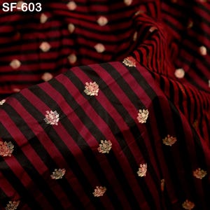 May include: Close-up of a fabric with a striped pattern in black and burgundy. The fabric has gold floral accents and the text "SF-603" in the upper left corner. The fabric is likely used for clothing or home decor.