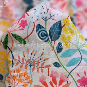 Pode incluir: Um tecido branco com uma estampa floral colorida. A estampa apresenta flores e folhas rosa, amarelas, laranja, azuis e verdes. O tecido é macio e leve, o que o torna perfeito para uma variedade de projetos de costura.