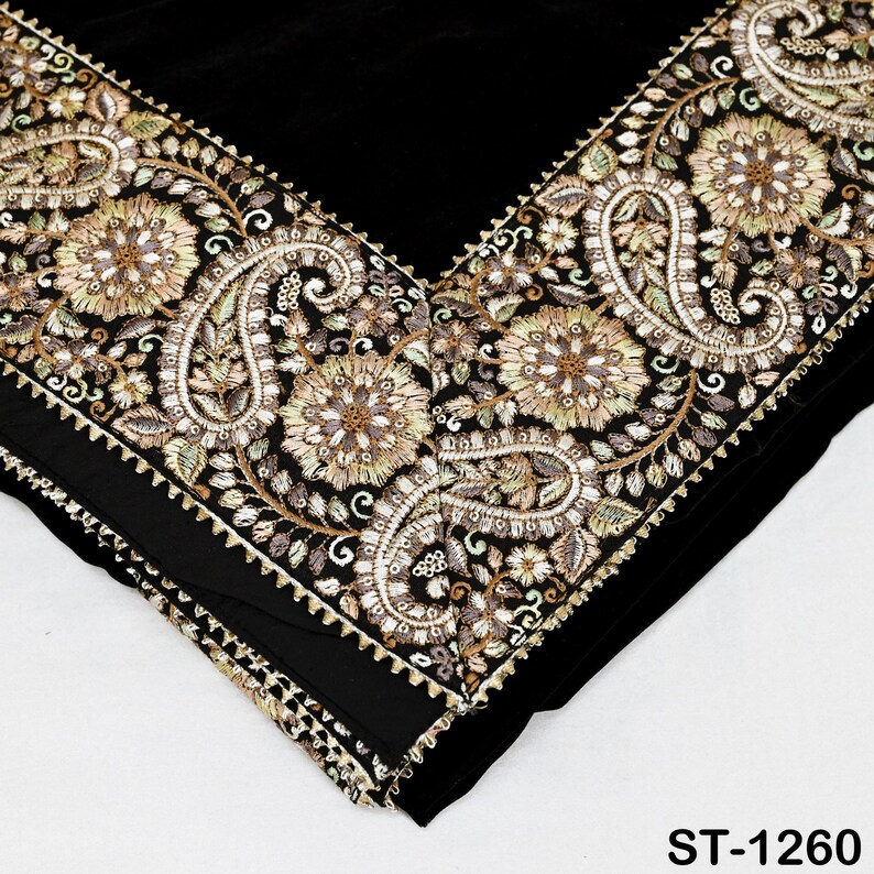 以下が含まれることがあります： 金、緑、クリーム色の複雑な刺繍が施された黒い織物。 デザインは、縁に沿って花柄とペイズリー柄が特徴です。 この織物はベルベットのような質感とスカラップのボーダーを持っています。