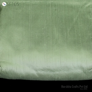 Pode incluir: Um close-up de um tecido liso verde claro com um brilho sutil. O tecido tem uma superfície ligeiramente texturizada e um degradê de um verde mais escuro na parte superior para um verde mais claro na parte inferior. O tecido é etiquetado como "SF105".