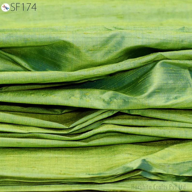 May include: A close-up of a folded green fabric with a subtle sheen. The fabric has a smooth, silky texture and is likely made of silk.