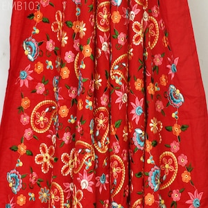 May include: Red fabric with intricate embroidery featuring paisley patterns and floral designs in shades of pink, blue, green, and orange. The fabric is embellished with gold thread and sequins.